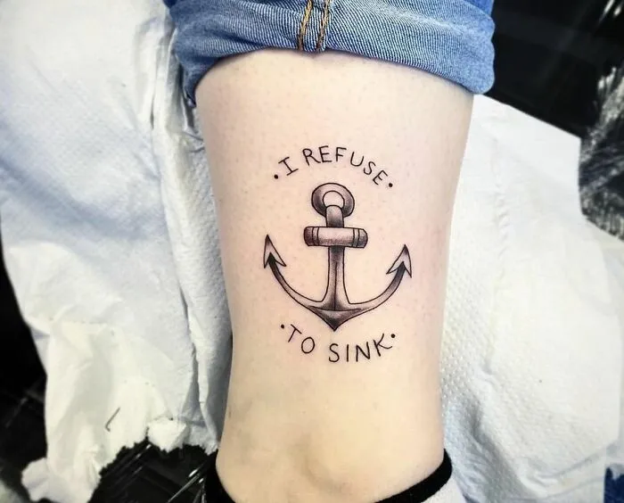 Anchor tattoo on thigh with words "I refuse to sink," symbolizing powerful mental health and resilience.