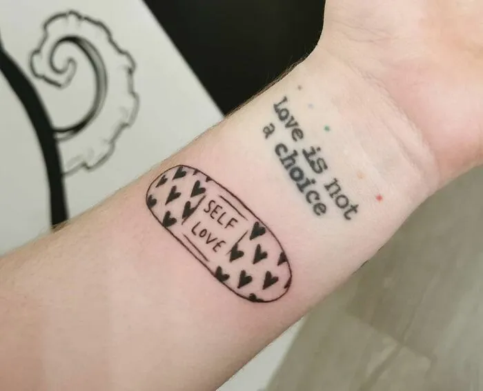 Arm tattoo with a band-aid design reading "self love" and text "love is not a choice," symbolizing mental health healing.