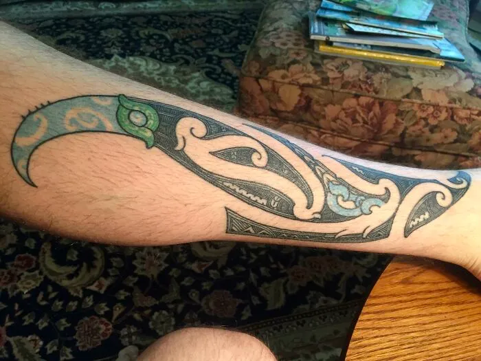 Tribal tattoo design on a person's forearm in a detailed and colorful style, showcasing intricate patterns.