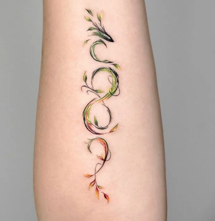 Abstract infinity tattoo on arm, featuring colorful leaves and intricate design elements.