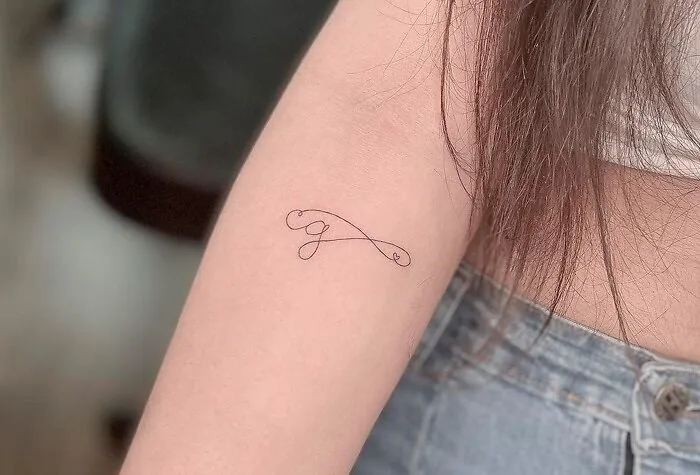 Minimal infinity tattoo on person's arm, showcasing eternal creativity.