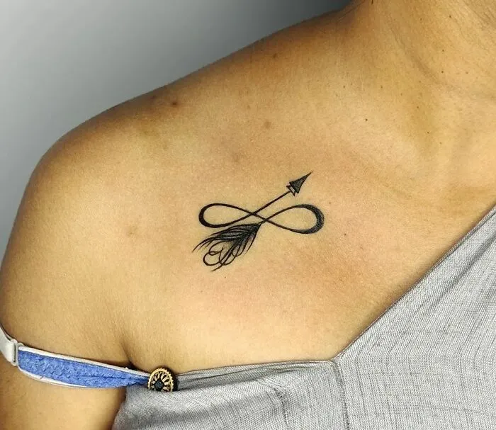 Infinity tattoo with arrow design on shoulder, symbolizing eternal creativity.