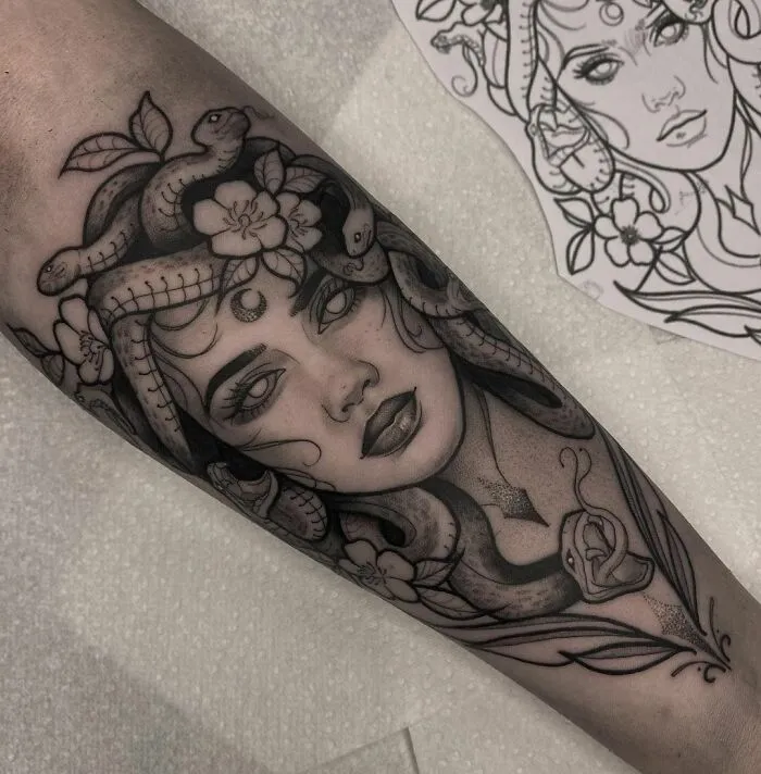 Medusa-inspired mental health tattoo, featuring snakes and floral elements on a forearm.