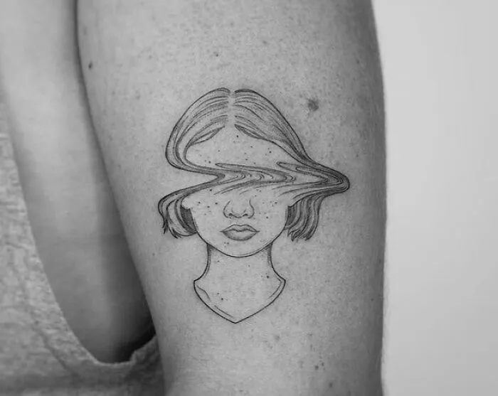Tattoo of a woman's face with a distorted line across the eyes, symbolizing mental health and healing.