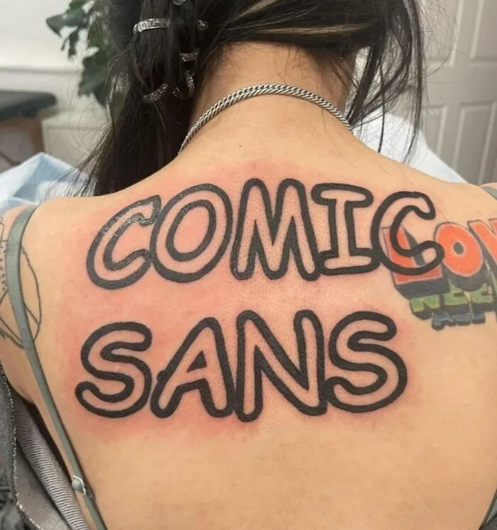 Back tattoo in bold Comic Sans font, showcasing a quirky tattoo choice.