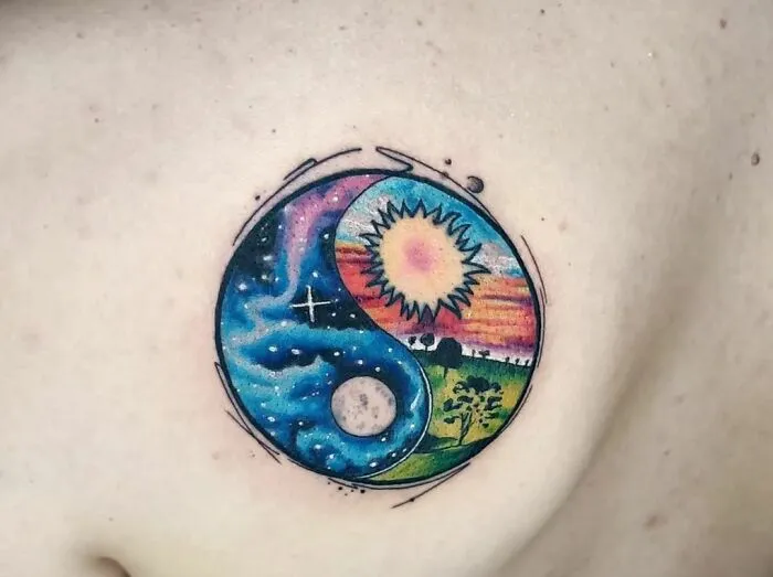 Colorful Yin Yang tattoo with sun and moon design on skin.