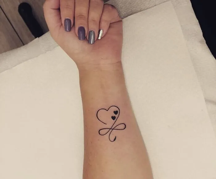 Heart and infinity symbol tattoo on forearm, showcasing creativity.