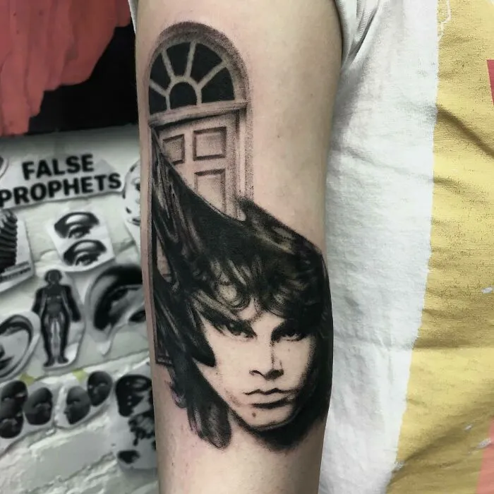 Music tattoo of a face and door on a person's arm.