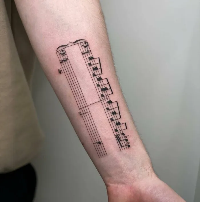 Music tattoo on forearm featuring a detailed staff and notes design.