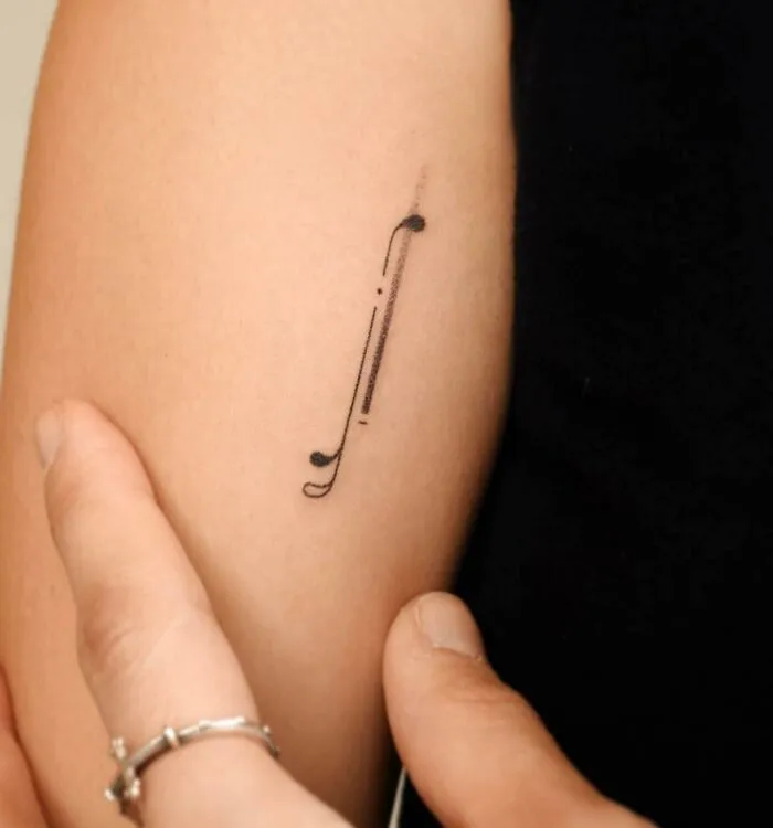 Minimalist music tattoo on forearm, featuring a simple musical symbol design.
