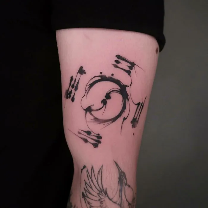 Abstract Yin Yang tattoo design with brushstroke effect on arm.