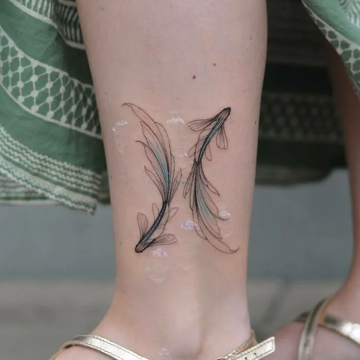 Ornate yin yang tattoo of two fish on a person's leg, showcasing duality in delicate line work.