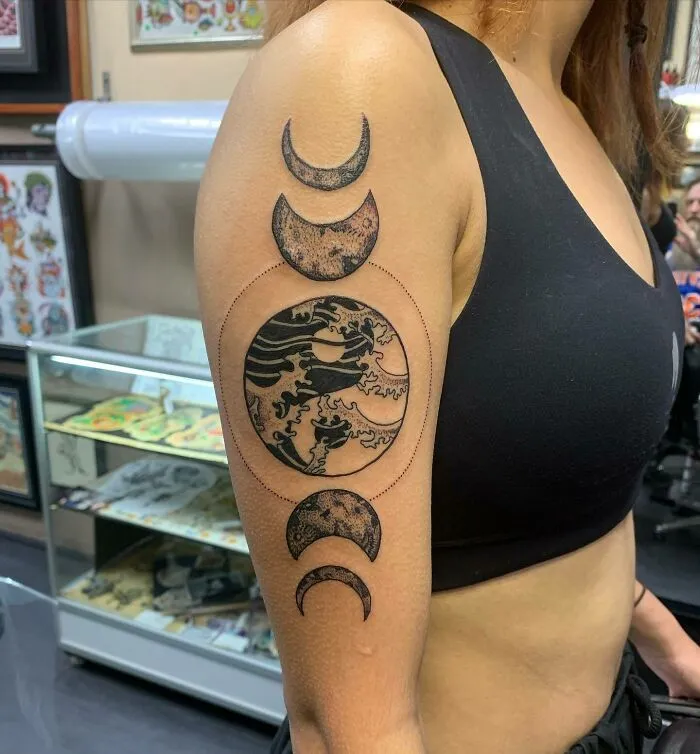 Close-up of a yin yang tattoo on a woman's arm, featuring crescent moon phases in a tattoo studio.