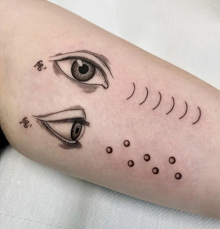Science tattoo featuring detailed eyes with scientific figures on skin.