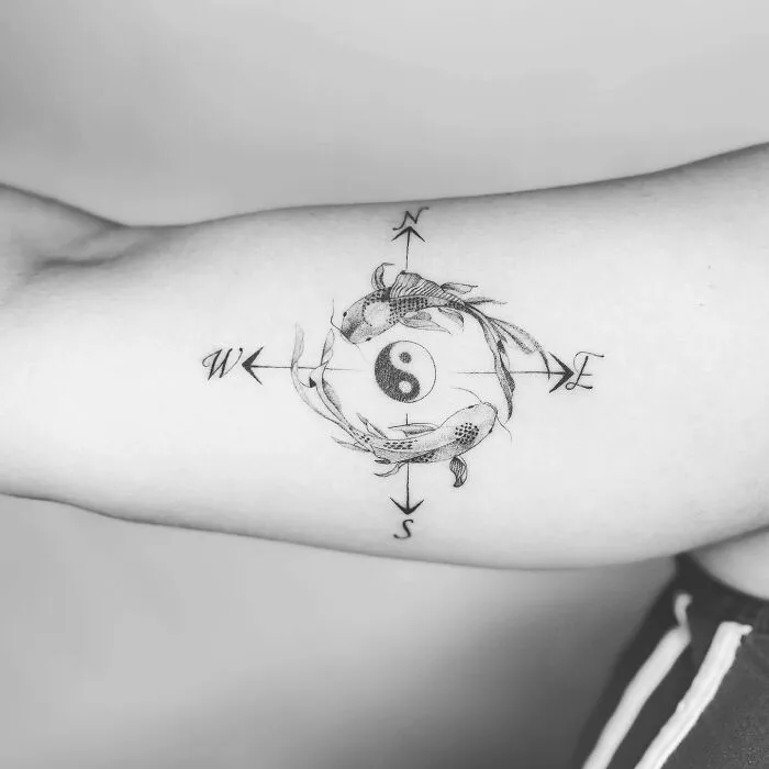 Yin Yang tattoo with koi fish and compass design on forearm.