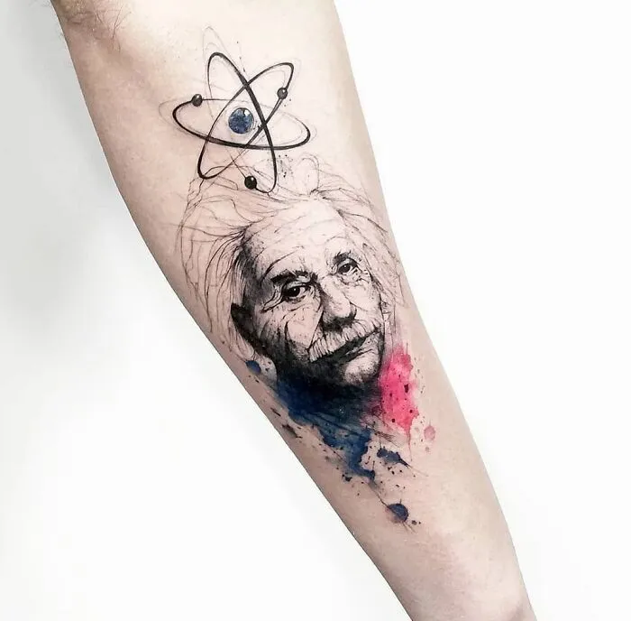 Science tattoo featuring Albert Einstein with an atom design and watercolor splashes on an arm.