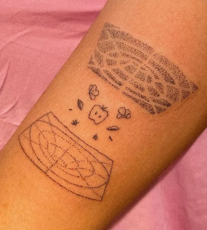Science tattoo with geometric patterns and an apple, showcasing a creative design on the forearm.