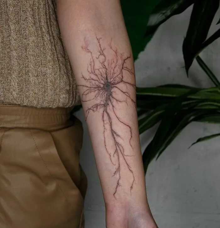 Science tattoo of a neuron design on forearm, depicting intricate nerve cell structure, for science enthusiasts.