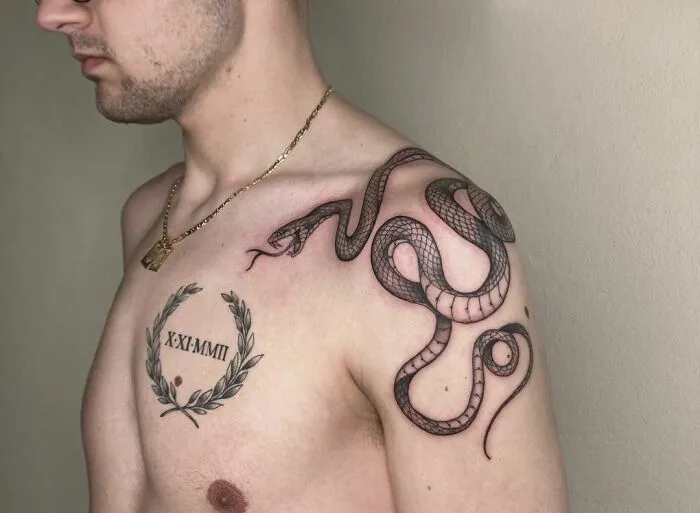 Man with an intricate snake tattoo across his shoulder and chest.