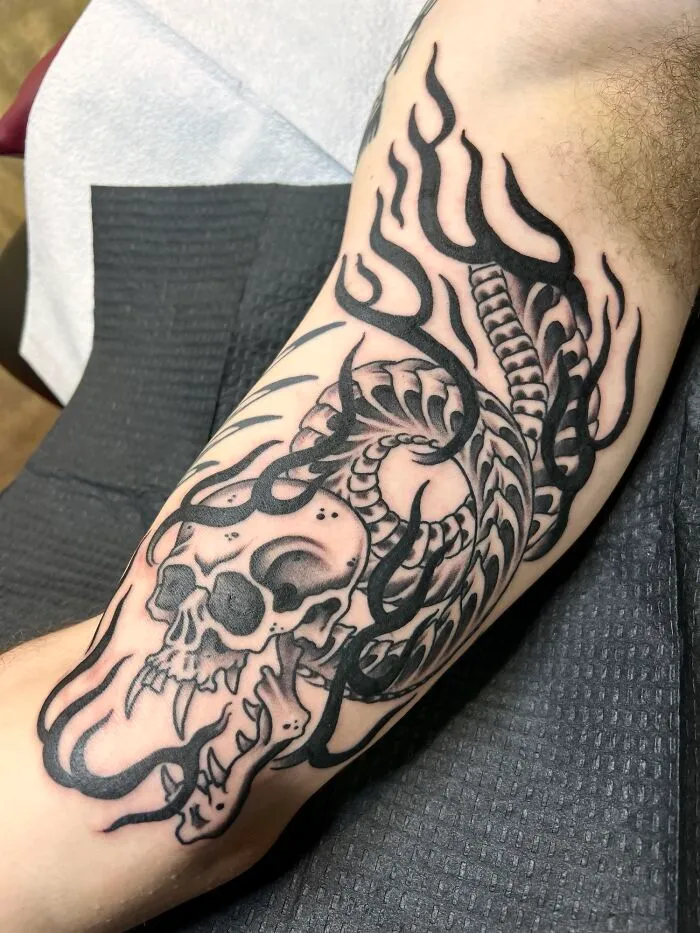 Snake tattoo design featuring skull and flames on inner arm.