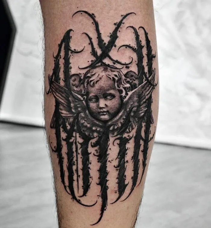 Gothic tattoo of an angel with intricate dark designs on a leg.