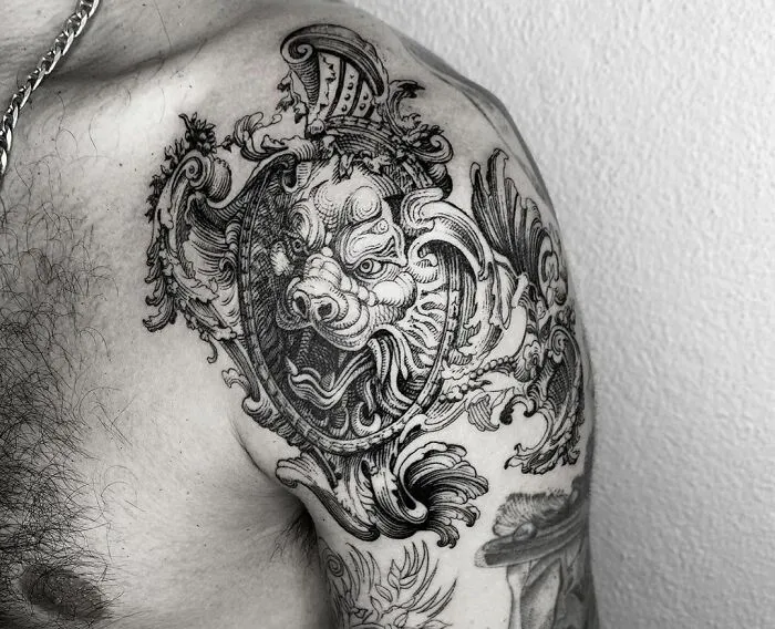 Intricate gothic tattoo on shoulder featuring a snarling boar adorned with ornate shield details.