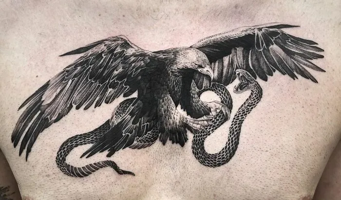 Gothic tattoo of an eagle and snake on the chest, intricately detailed in black ink.