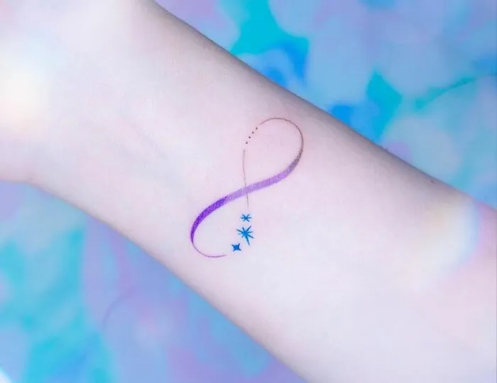 Abstract infinity tattoo with stars on wrist, showcasing eternal creativity.