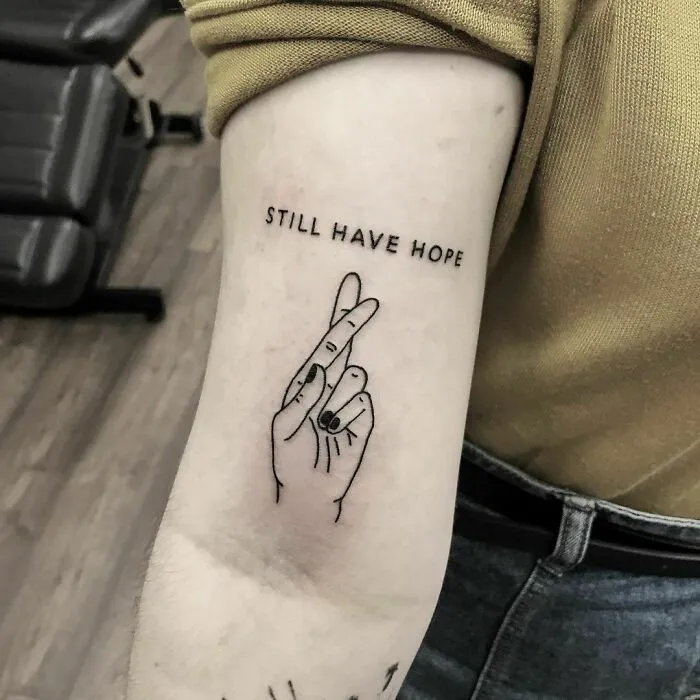 Crossed fingers tattoo with "Still Have Hope" text, symbolizing powerful mental health support.