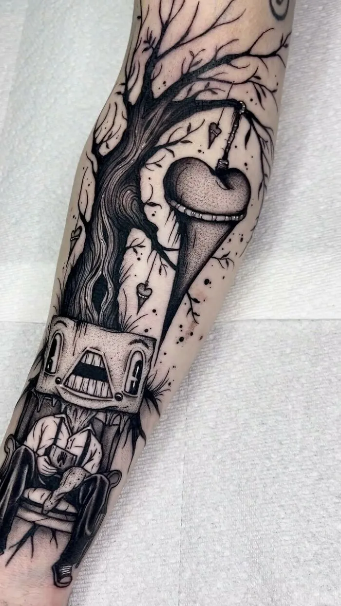 Gothic tattoo of a tree with hanging heart and a figure sitting, showcasing intricate line work on the forearm.