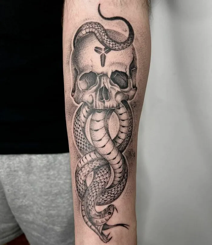 Snake tattoo intertwining with skull design on a forearm.