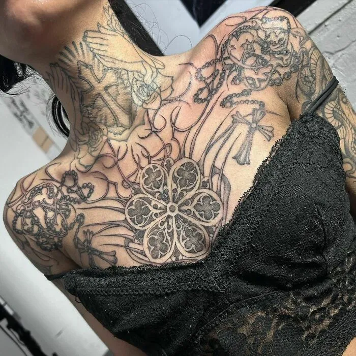 Intricate tribal tattoo on a woman's neck and chest showcasing detailed designs and symbols.