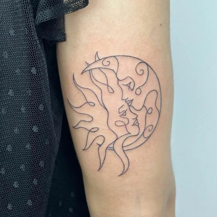 Minimalistic yin yang tattoo of sun and moon on arm, symbolizing duality of life.
