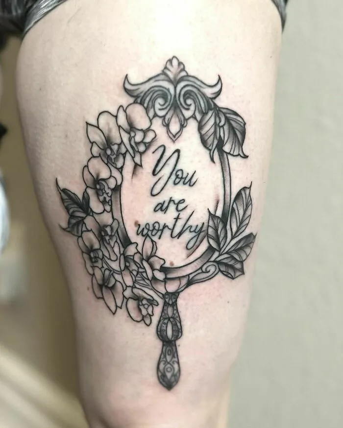 Ornate mirror tattoo on skin with floral design and "You are worthy" text, symbolizing mental health healing.