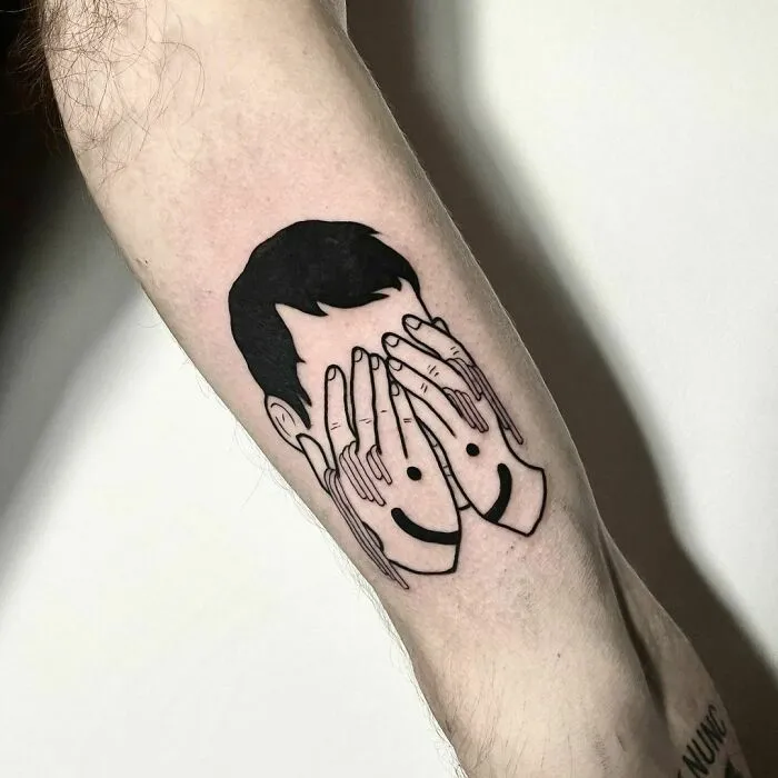 Tattoo of a person covering their face with hands featuring smiley faces, symbolizing mental health themes.