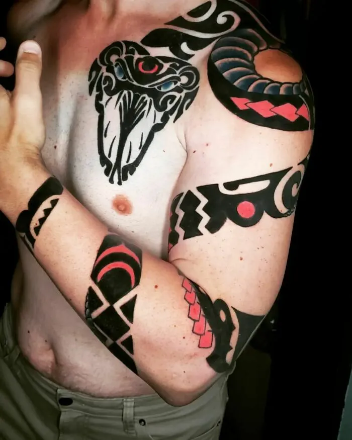 Arm with tribal snake tattoos, featuring bold patterns and vibrant colors, wrapping around bicep and shoulder.