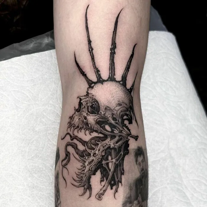 Gothic tattoo depicting a skeletal creature with spikes on an arm.
