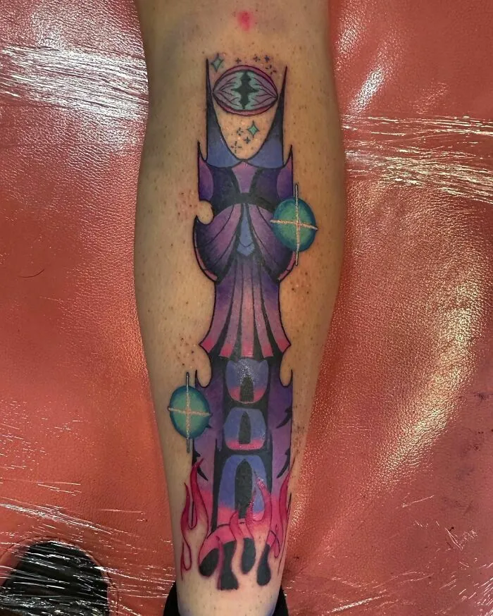 Colorful Lord of the Rings tattoo featuring a stylized design on a person's leg, with vibrant shades of purple and pink.