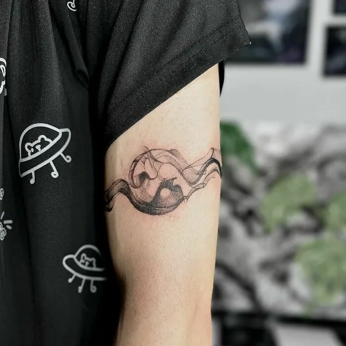 Abstract yin yang tattoo design on upper arm showcasing duality.