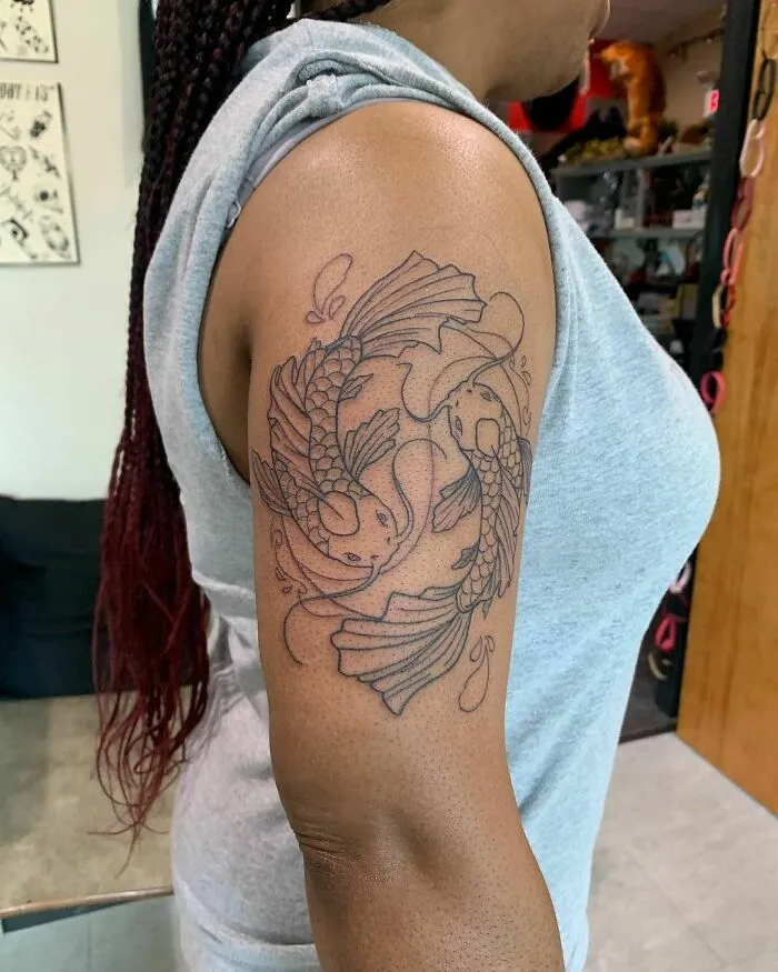 Yin Yang tattoo on a person's arm featuring koi fish, symbolizing duality and balance in life.