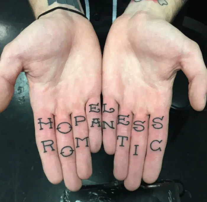 Tattoo mistake on fingers, showing a permanent ink error with misspelled words.