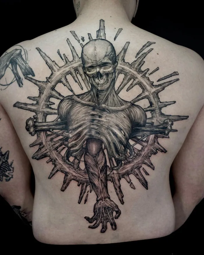 Gothic tattoo featuring a skeletal figure with detailed anatomy and circular design on a person's back.