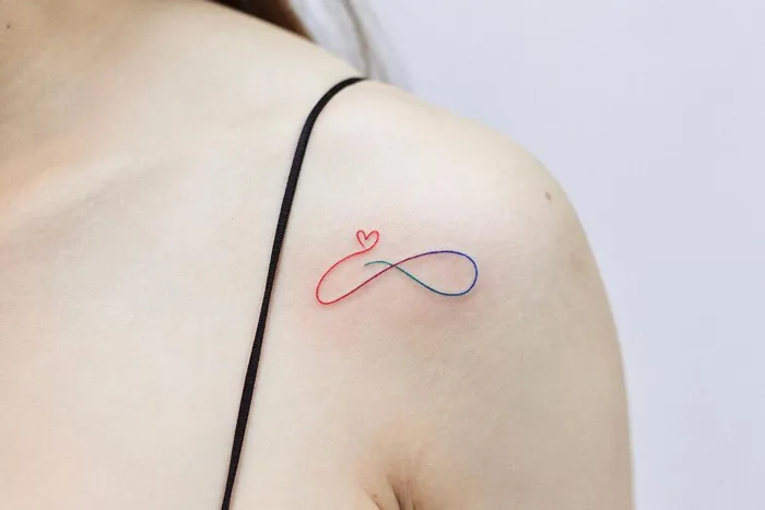 Colorful infinity tattoo with a heart on a person's shoulder, showcasing eternal creativity.