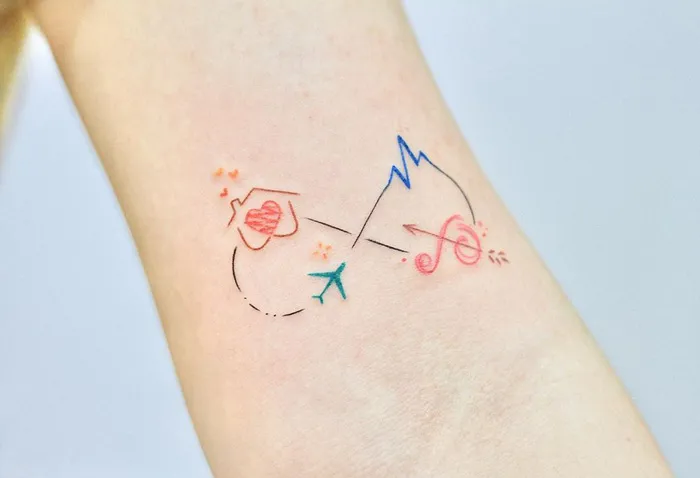 Colorful infinity tattoo featuring a plane, heart, and mountain on a forearm, symbolizing eternal creativity.