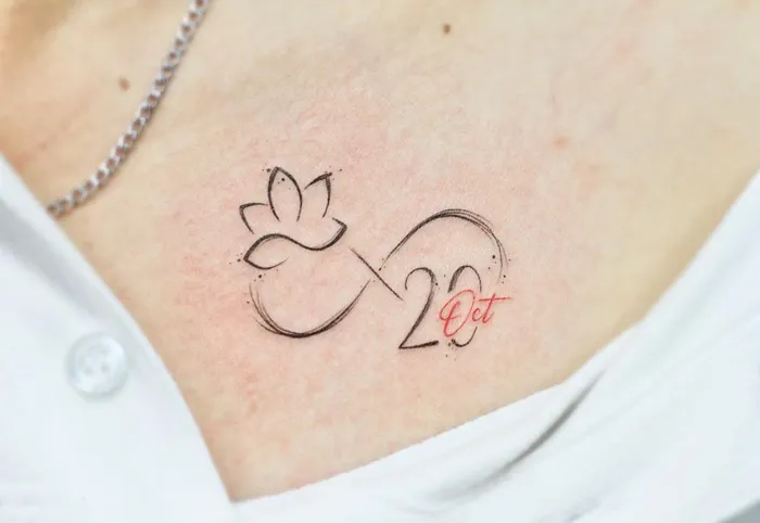 Infinity tattoo with a lotus and date, symbolizing eternal creativity.