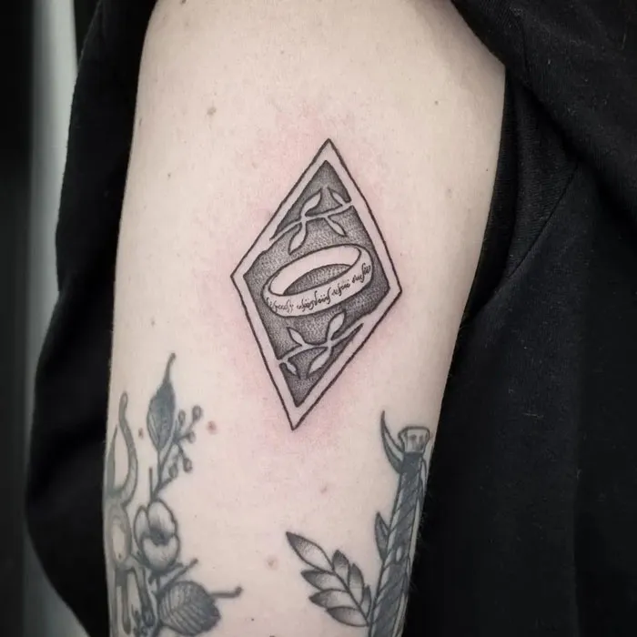 Tattoo of the One Ring in a diamond shape with elvish script from Lord of the Rings on an arm.