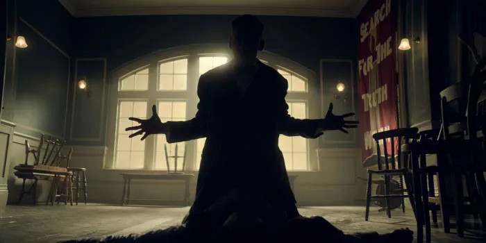 Arthur Shelby kneeling on the ground in the background of a window