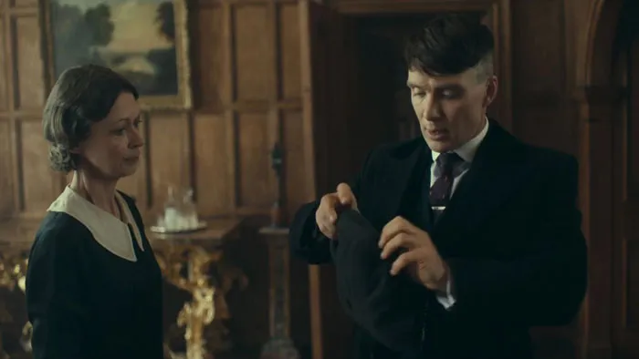 Tommy Shelby putting on a hat