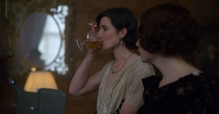 Lizzie Shelby holding a cigarette and drinking