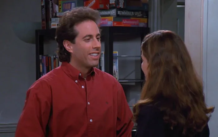 Jerry wearing a red shirt smiling and talking in a scene that reflects funniest Seinfeld quotes about everyday life.